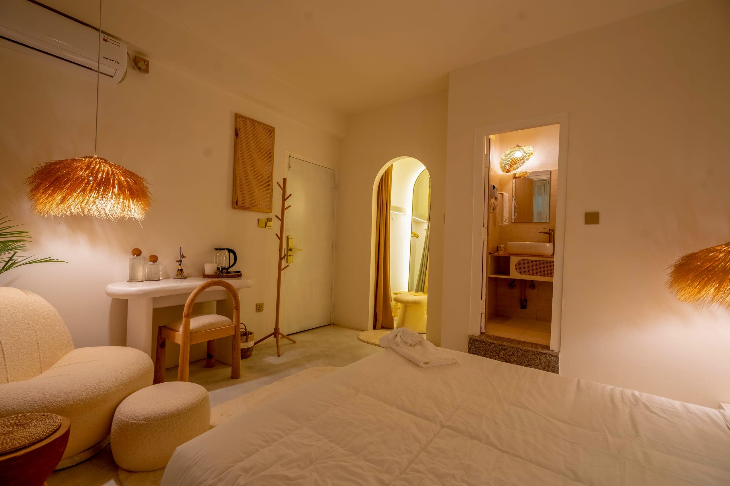 Deluxe Bedroom overview from the bed toward the desk, the arched doorway and the bathroom