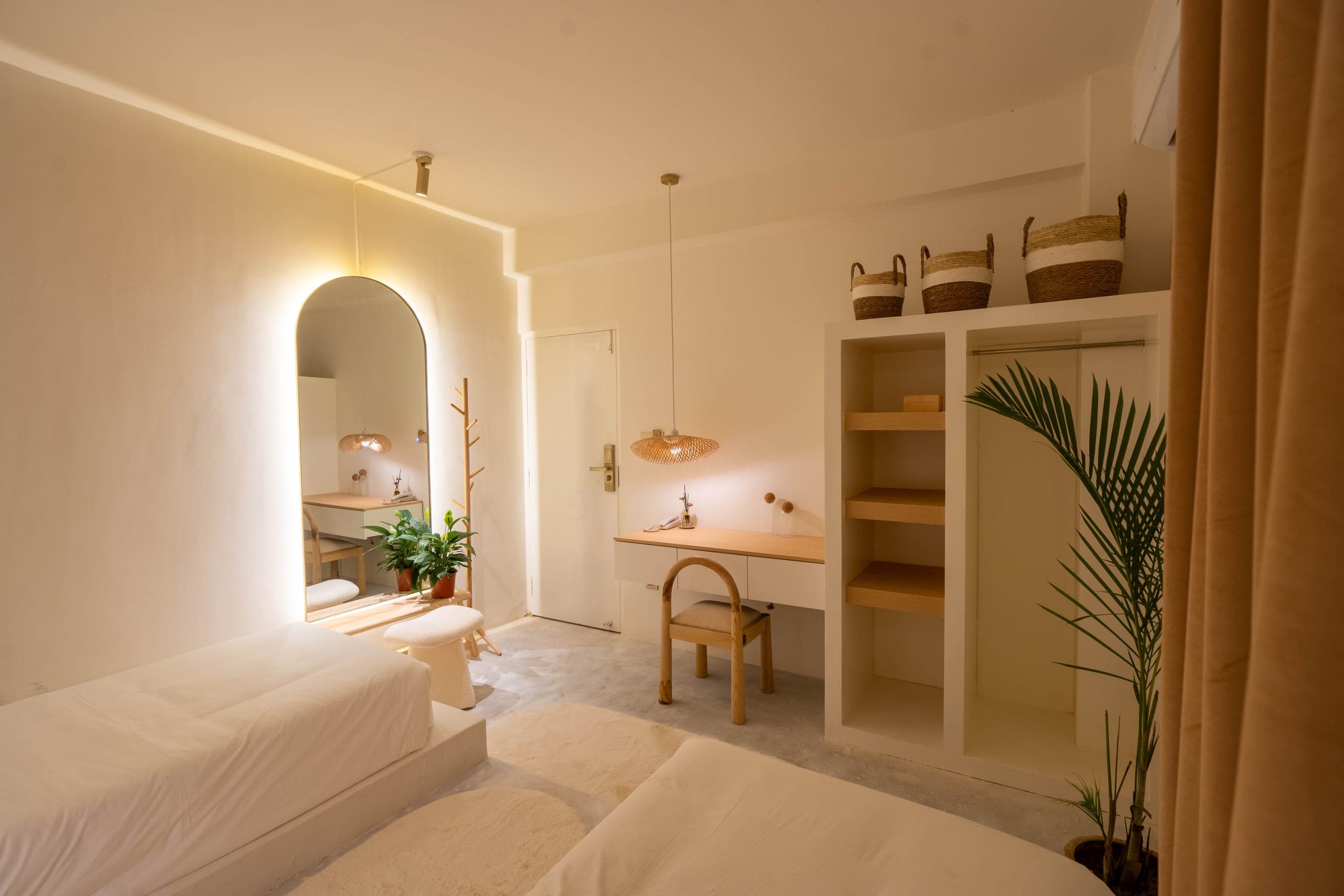Second room of the suite with two platform beds, a floating oak desk, open shelves and an arched mirror