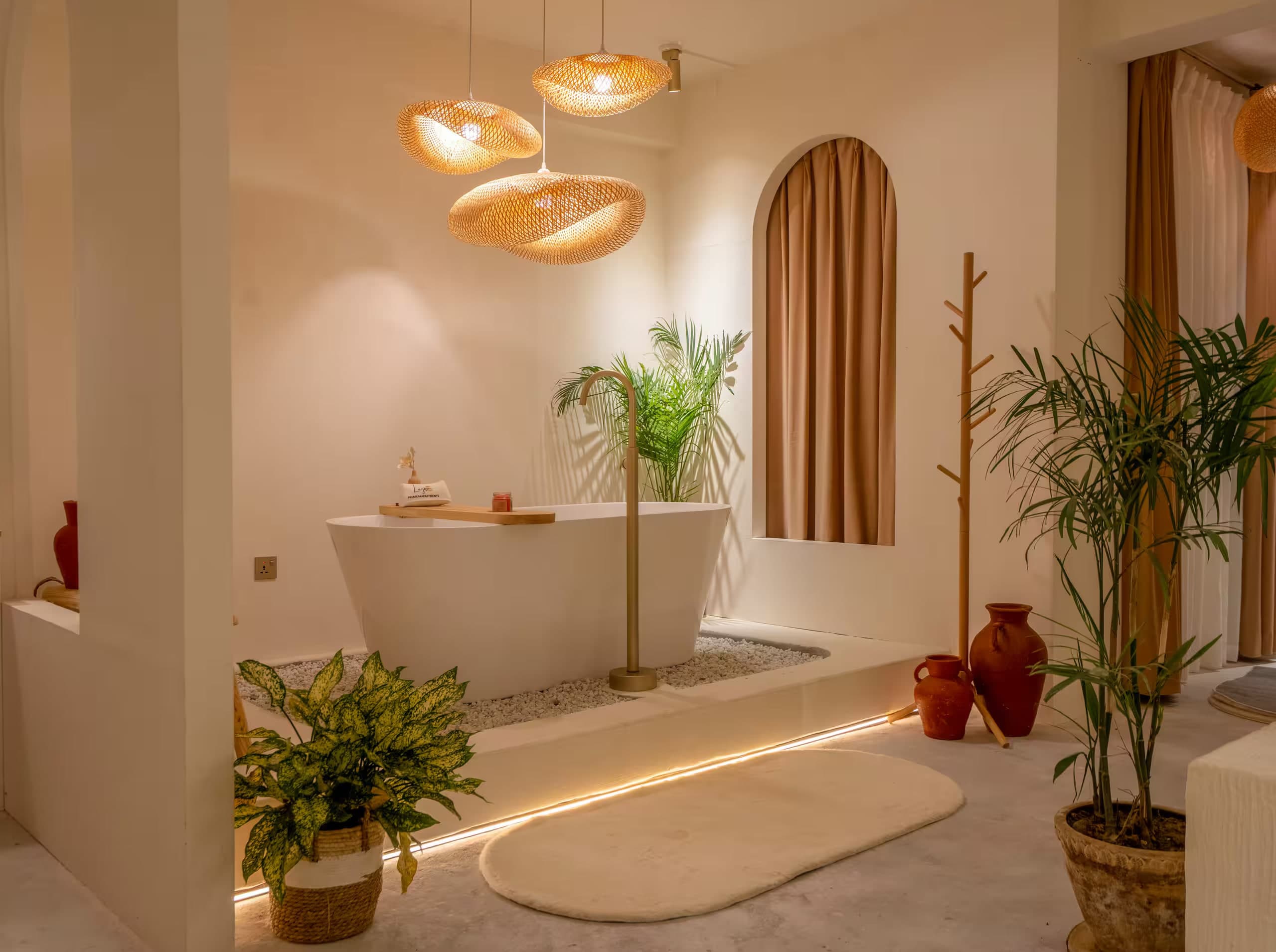 Freestanding bathtub on white pebbles, palms and an arched terracotta curtain at Lagom
