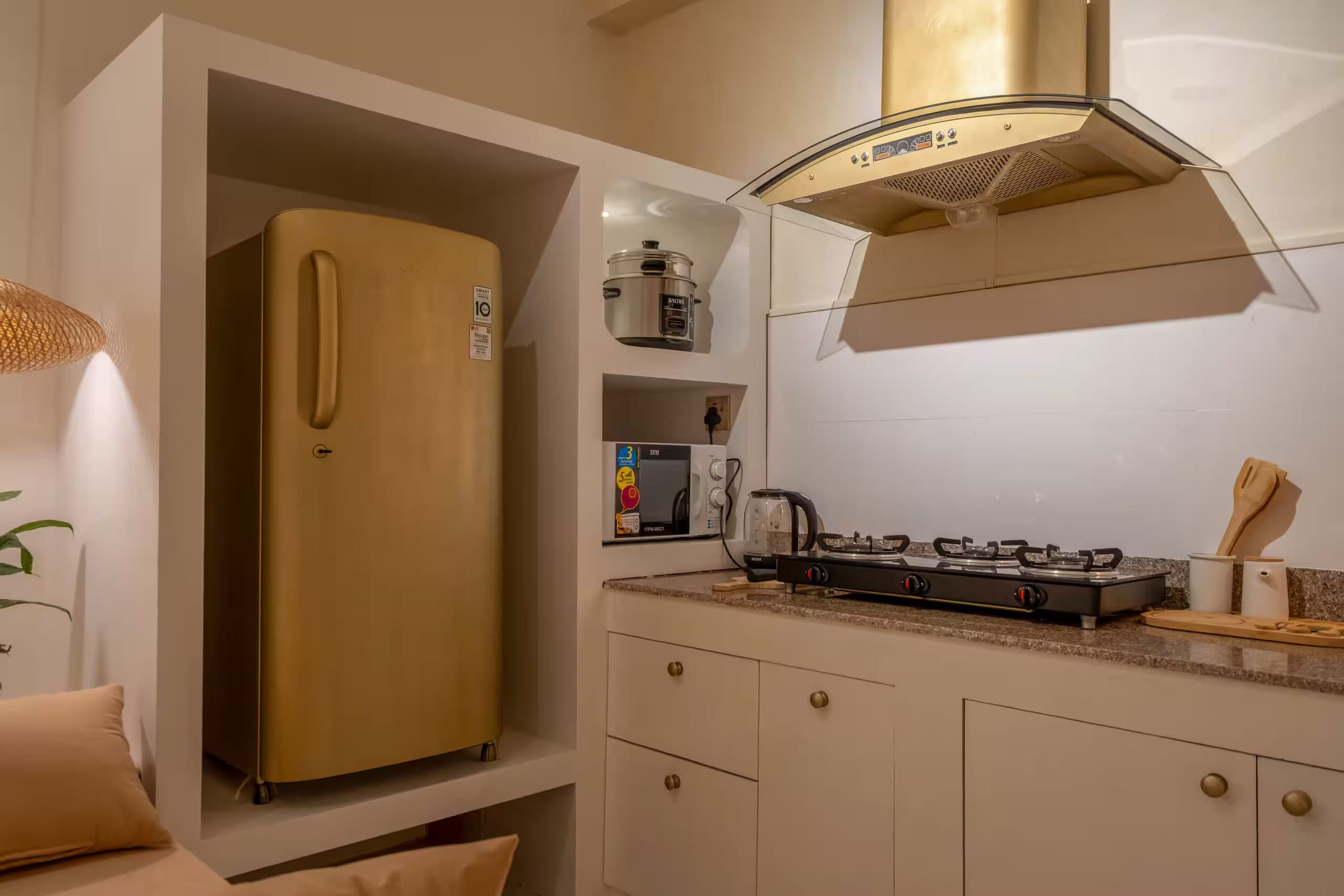 Lagom kitchen with a gold fridge, brass hood and stone counters