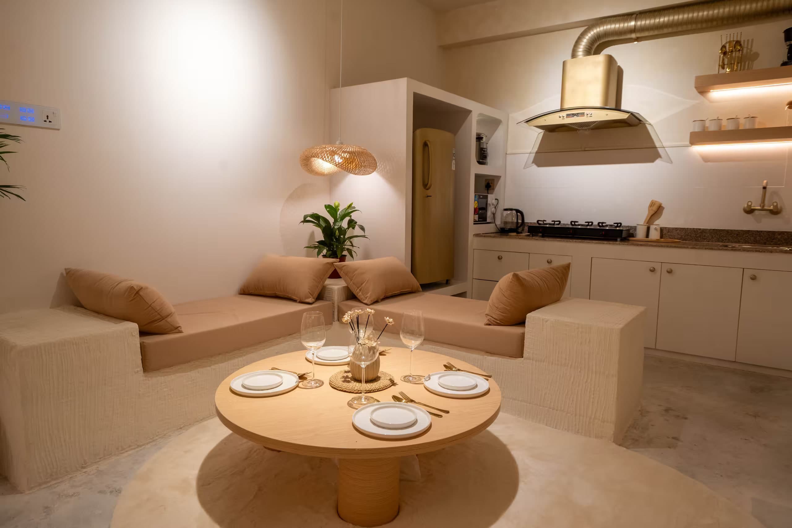 Lagom living room with a round oak table, built-in plaster sofas and an open kitchen with a brass hood