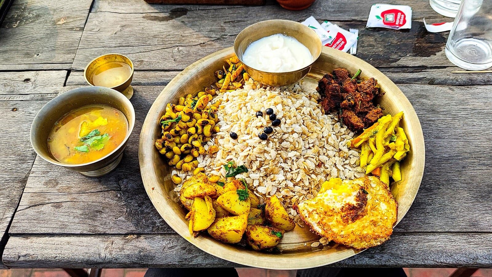 Samay baji, the Newari platter, on a brass plate: beaten rice, choila, black soybeans, fried egg, potatoes and curd
