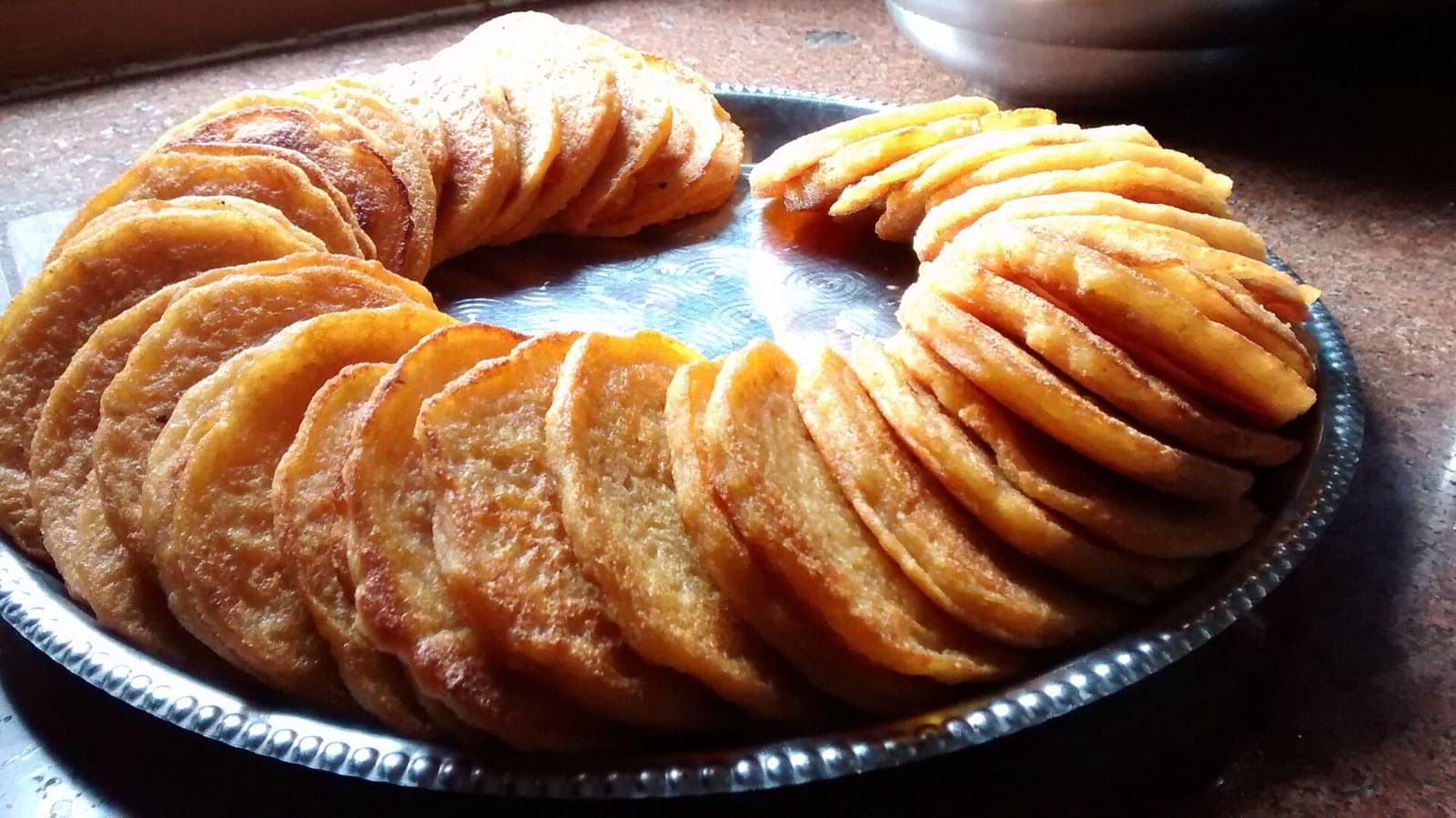 A plate of golden wo, Newari lentil pancakes, stacked in a ring