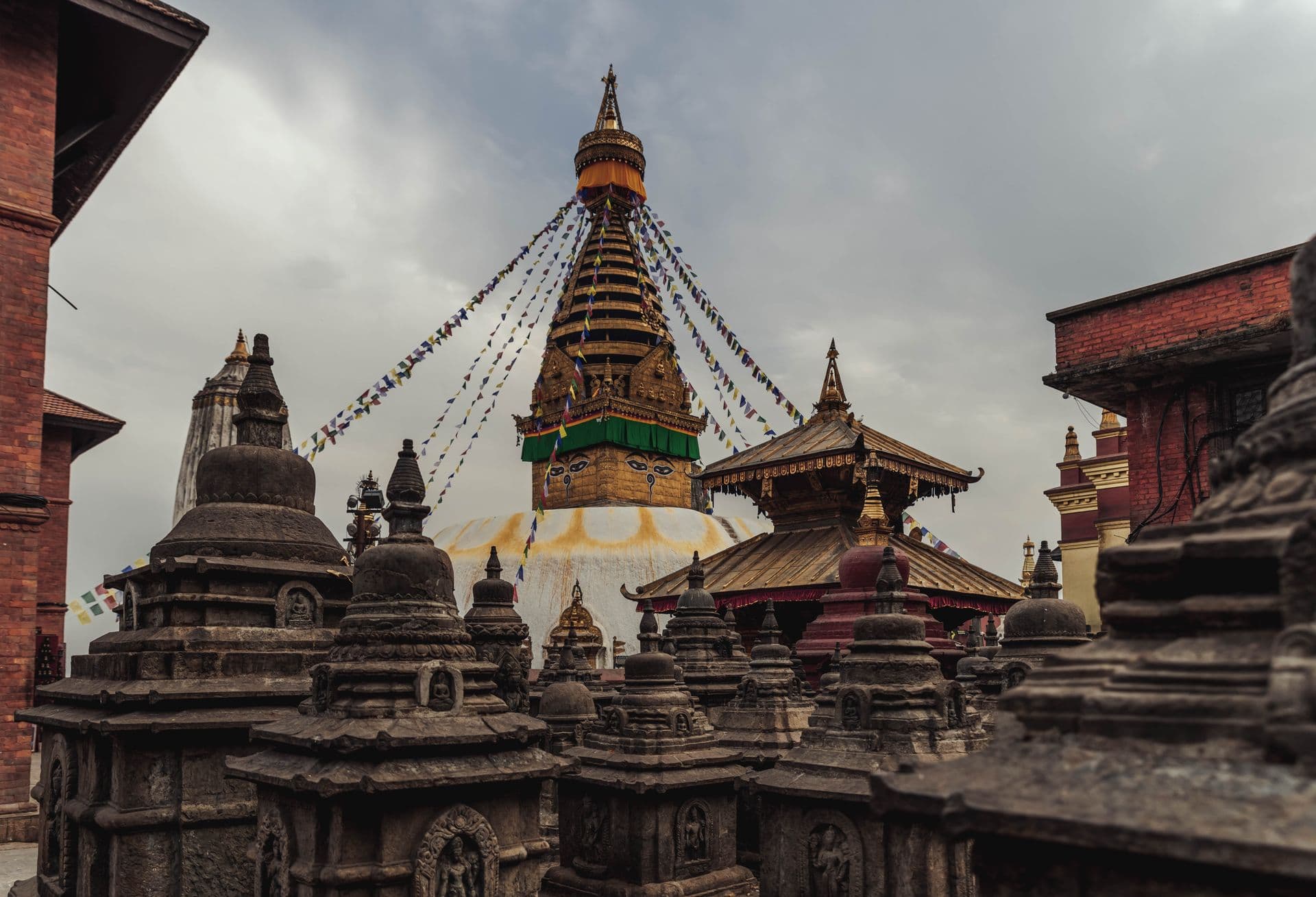 Swayambhunath Stupa's golden tower and painted eyes rising above a field of small carved stone shrines